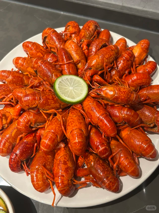 不锈钢蒸锅内正在蒸制小龙虾，蒸汽翻腾，虾体已变为鲜艳红色，整齐排列于竹制蒸屉上