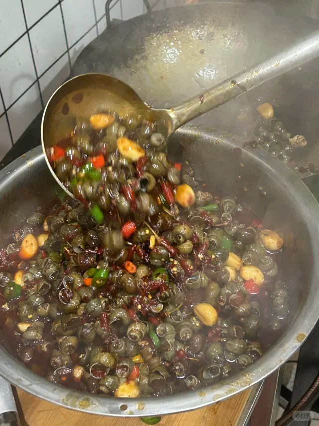 中式炒锅内正在进行高温翻炒的酱爆螺丝椒,菜品色泽红亮,酱汁浓稠地附着在辣椒表面,体现‘锅气足、火候准’的烹饪精髓 烹饪过程图:一口铁锅中正在翻炒的酱爆螺丝椒,食材呈深棕色带油光,锅气升腾,厨师手持锅柄进行颠勺动作