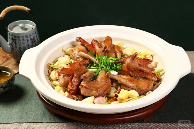 深色砂锅内正在冒泡的老姜炖鸽子汤,汤色乳白微黄,可见大块老姜与完整鸽体,表面浮有少量金黄油星,旁边放置木勺,展现家常炖煮场景 砂锅中文火慢炖的老姜鸽子汤特写