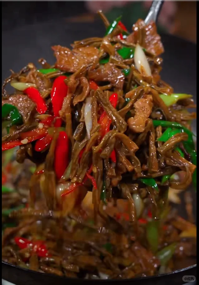 高清美食摄影:铁锅中刚出锅的冷冻豆角炒腊肉,豆角段翠绿油亮、形态完整无软边,表面裹薄油光,可见细微焦斑;搭配金黄腊肉片与青红椒丝,撒白芝麻点缀;背景虚化呈现灶台烟火气 冷冻豆角爆炒成品特写