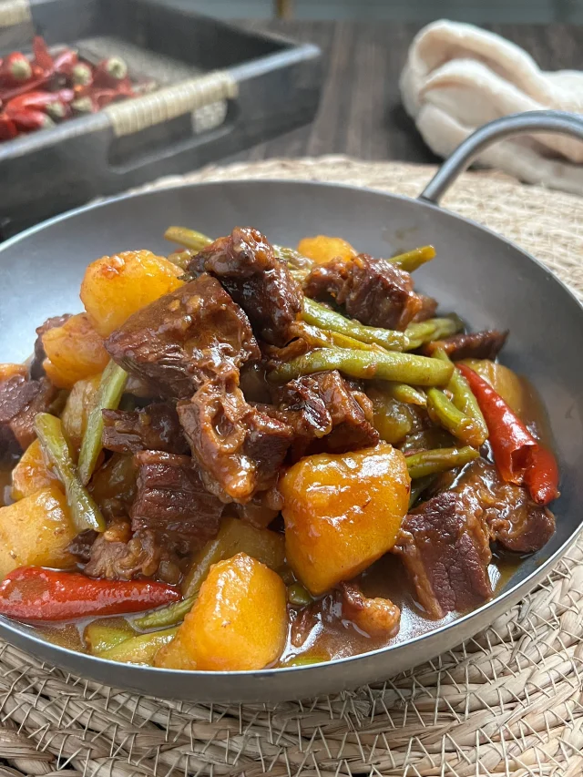 成品牛肉土豆装盘效果:酱汁浓稠挂勺,牛肉酥软有弹性,土豆块完整微透,葱花鲜亮,展现‘酥而不柴、糯而不烂’质感 成品牛肉土豆特写:深褐色酱汁浓亮裹满牛肉与土豆,牛肉块形完整微颤,土豆表面柔光半透明,撒翠绿葱花,背景为青花瓷炖锅