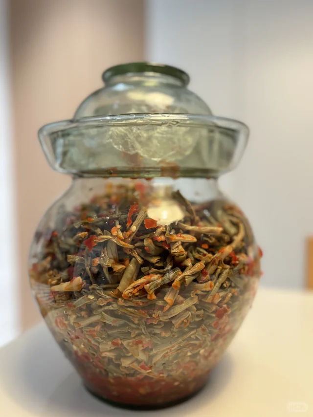 高清实拍对比图:自然光照下的豆角晾晒过程(左)与家庭自制风味盐渍豆角成品(右),突出原料形态、容器材质及环境洁净度 豆角传统保存对比图:左侧为阳光下竹匾上摊开晾晒的浅绿色豆角条,右侧为玻璃密封罐中浸泡在琥珀色料汁里的脆豆角,罐体标签清晰标注“7日风味腌豆角”