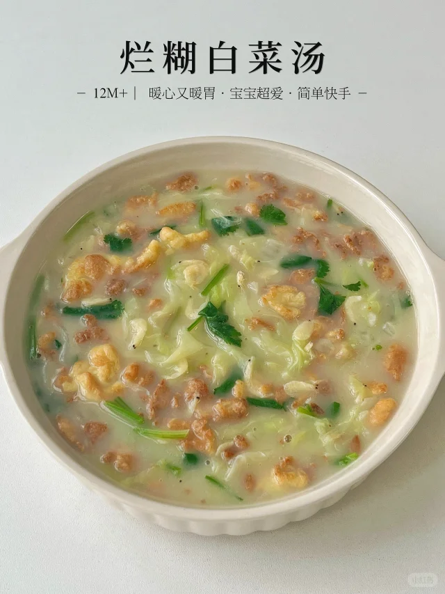 一盘刚出锅的烂糊白菜盛放在白色瓷盘中,色泽柔和,白菜条呈金黄色调,表面覆盖一层晶莹透亮的薄芡,汤汁呈乳白色,隐约可见姜末点缀其中,整体散发热气,展现温暖诱人的家庭烹饪氛围 烂糊白菜成品特写