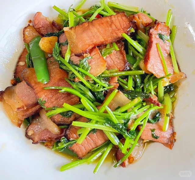 香菜炒腊肉高清成品图,突出腊肉油润、香菜碧绿、锅气升腾的视觉冲击,展现川渝家常菜的烟火质感 重庆大叶香菜炒腊肉成品特写:油亮腊肉片卷曲,翠绿香菜茎叶分明,青蒜苗点缀其间,锅气氤氲,盛于青花瓷盘