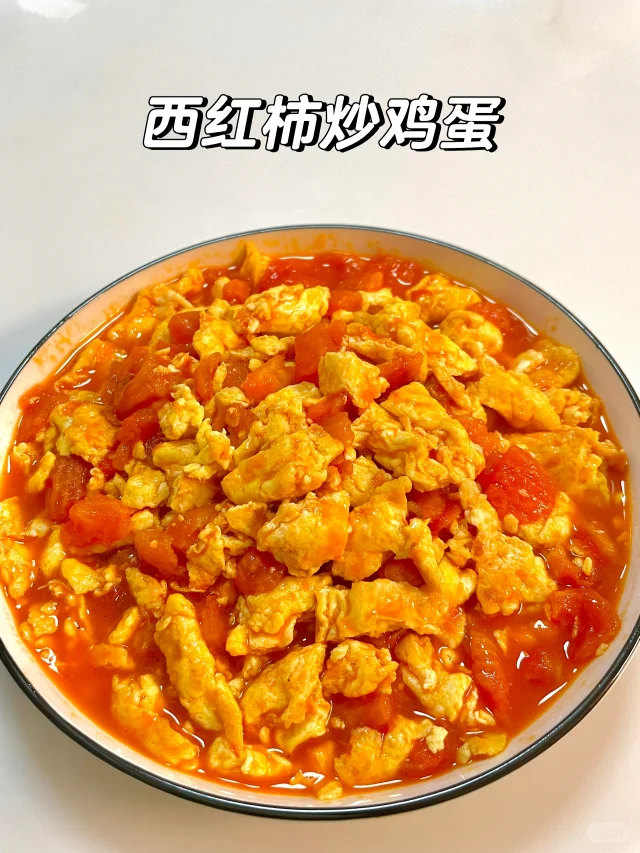 锅中正在翻炒的西红柿与鸡蛋混合物，红汁四溢，蛋块蓬松金黄，热气腾腾
