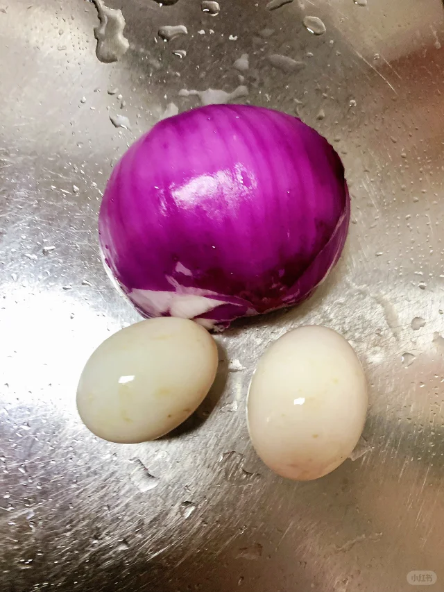 一盘刚出锅的紫洋葱炒鸡蛋特写,紫色洋葱条与金黄鸡蛋交织,表面略带油光,摆放在白色瓷盘中,背景为家庭厨房环境 紫洋葱炒鸡蛋成品图