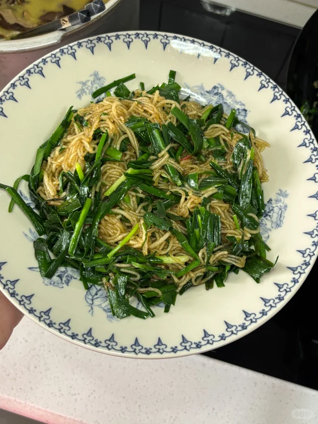 浆水面成品拌制特写：粗瓷大碗中乳白浆水面条上铺满翠绿油亮的炒韭菜，表面淋有半勺清亮浆水汤，可见韭菜根部微翘、叶尖舒展，无软塌出水现象