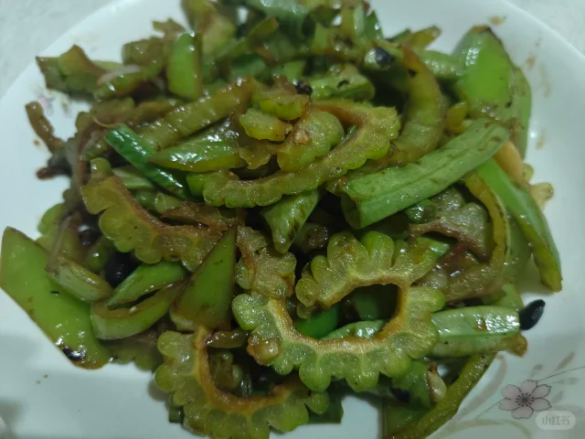 一盘刚出锅的清炒苦瓜菠菜,颜色鲜明,苦瓜呈淡绿色,菠菜为深绿色,表面略带油光,配有木质筷子夹起菜品的细节,体现家常健康风味 清炒苦瓜菠菜成品菜肴特写