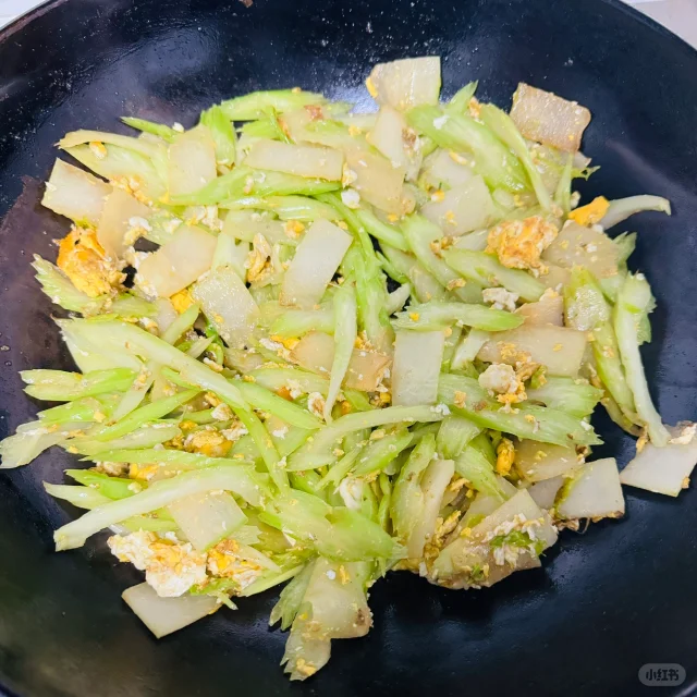 一盘刚出锅的冬瓜炒芹菜,冬瓜晶莹剔透,芹菜翠绿鲜亮,表面略有光泽,盘底无多余汤汁,背景为木质餐桌,营造温馨家常氛围 冬瓜炒芹菜出锅图