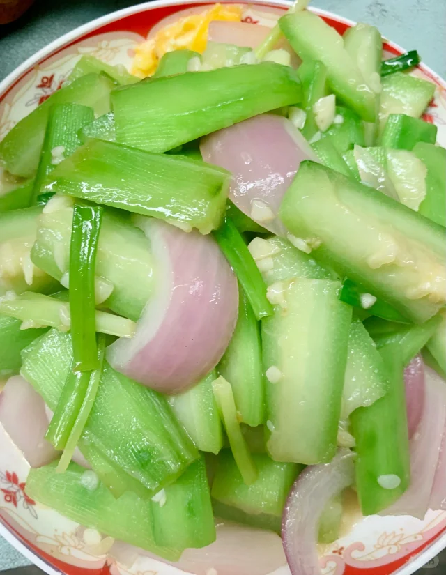 清炒丝瓜成品特写：翠绿透亮、形态完整、油润不水塌，盘底仅有微量清汤，撒少许白芝麻