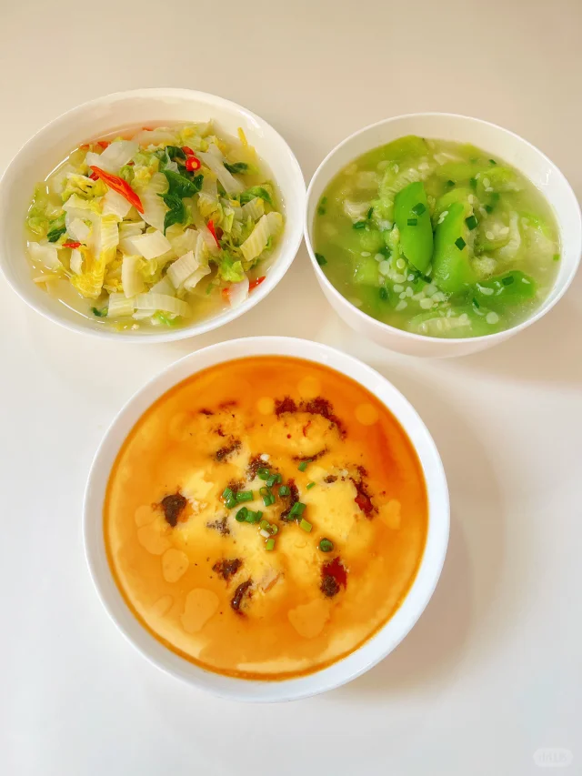 一张家庭餐桌上摆放着三道以白菜为主料的家常菜:清炒白菜、白菜豆腐汤和酸辣白菜,配米饭和小碟酱菜,营造温馨健康的饮食氛围 家庭餐桌上的白菜菜肴