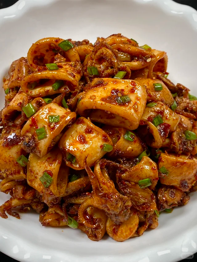 冰鲜鱿鱼焯水过程特写：不锈钢锅中清水沸腾，数片鱿鱼圈正在翻滚，边缘已呈现自然卷曲弧度，水面浮起细微泡沫，计时器显示01:15