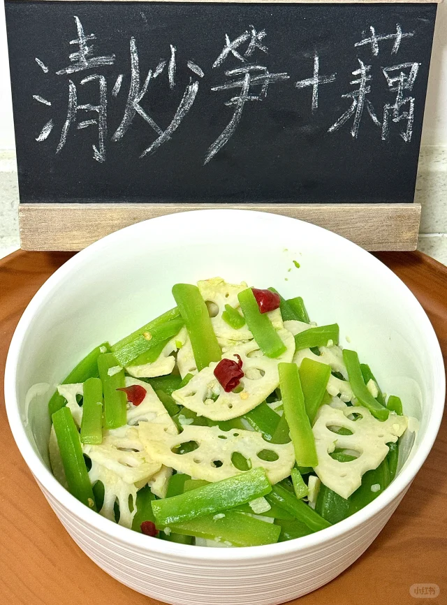 莲藕春笋快炒过程图:展示专业控温翻炒手法,强调食材保持脆嫩质地与自然色泽,佐证科学烹饪对营养保留的关键作用 厨师正在中式炒锅中翻炒莲藕片与春笋片,食材呈半透明脆亮状态,锅气升腾,配蒜末与青红椒丝,体现“快火清炒”工艺要点