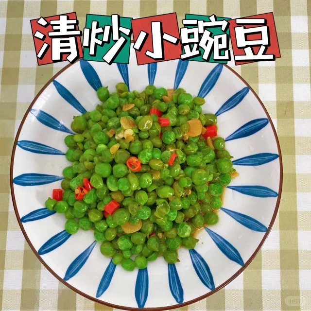 一个明亮的家庭厨房灶台,不锈钢炒锅中正翻炒着翠绿色的豌豆,旁边配有切好的红椒丁和葱段,厨师手持锅铲操作。台面上放有刚剥好的新鲜豌豆粒和空豆荚,展现从原料到成品的过程,突出豌豆作为家常食材的烹饪应用 家庭厨房中正在翻炒豌豆菜肴的场景