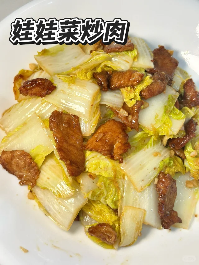 娃娃菜与五花肉在炒锅中翻炒，锅中有少量汤汁，五花肉呈金黄色，娃娃菜微微卷曲